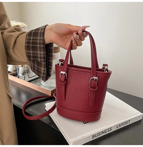 Détail du sac seau bordeaux en cuir grainé avec poignées et bandoulière réglable