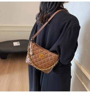 Brown quilted leather shoulder bag with gold chain strap worn by model in black suit