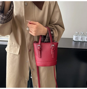 Détail du sac seau rouge en cuir grainé avec boucles argentées et bandoulière amovible