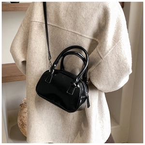 Glossy black patent leather mini boston bag styled on a beige textured wool coat