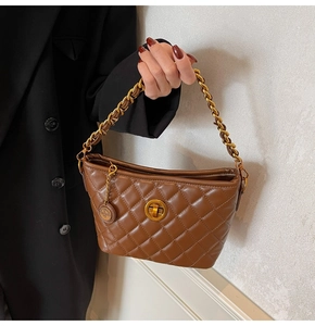 Detail of dark brown quilted shoulder bag featuring gold chain strap and turn-lock