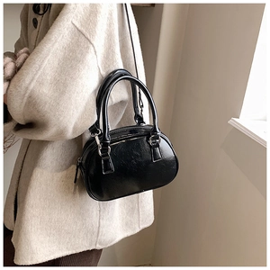 Glossy black patent leather mini handbag styled with a cream textured wool coat