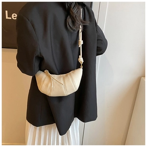 Detailed view of cream croissant bag featuring lychee texture and knotted shoulder strap