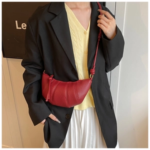 Detail of burgundy leather croissant bag showing pebble texture and metal zipper closure