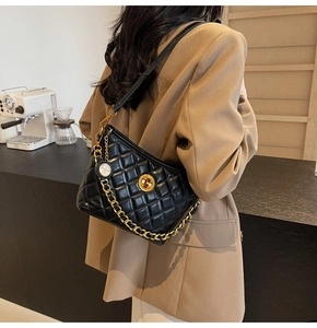 Quilted black leather bag with gold chain strap worn over a brown blazer