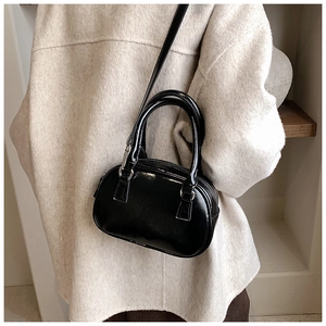 Detail of a black patent leather bowling bag showing its glossy finish and silver hardware