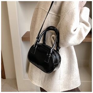 Close-up of a glossy black patent leather Boston bag with silver hardware on a shoulder