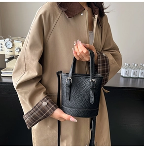 Détail du mini sac seau noir en cuir grainé avec bandoulière réglable et poignées