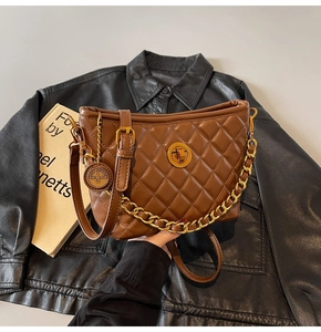 Close-up of brown quilted shoulder bag with gold twist lock and metal logo pendant