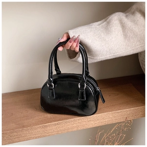Detail of glossy black patent leather bowling bag with silver metallic zippers