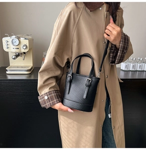Détail d'un mini sac seau en cuir grainé noir avec des sangles à boucle décoratives