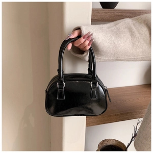Close-up of black glossy patent leather bowling bag with silver hardware and top handle