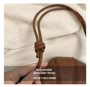 Close-up of brown lychee leather bag featuring vertical stitching and adjustable knot strap