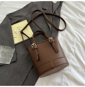 Détails d'un sac seau en cuir grainé marron foncé avec des boucles en métal argenté