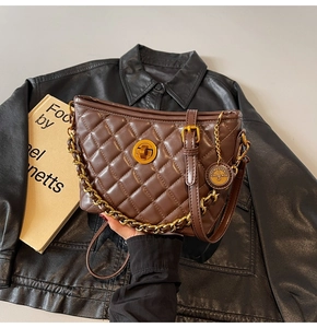 Detail of quilted brown leather bag with golden clasp and vintage chain strap accents