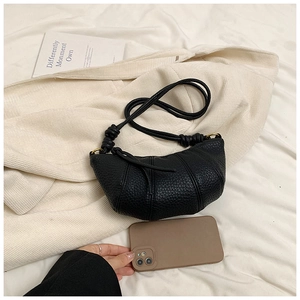 Close-up of black croissant bag with lychee texture and phone for size reference