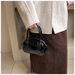Detail of glossy black patent leather bowling bag with twin handles and zip top