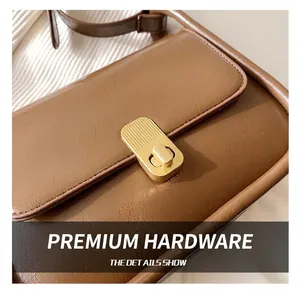 Detailed view of the vintage brown leather bag featuring a gold rectangular twist lock