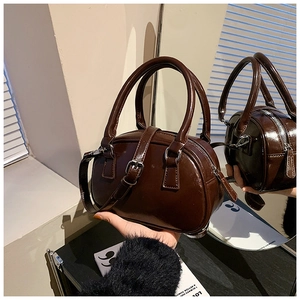 Close-up of a dark brown glossy patent leather bowling bag with metallic zipper detail