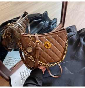 Macro detail of brown quilted leather bag featuring gold chain and turn-lock closure