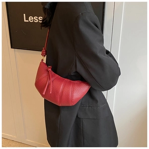 Detailed side view of dark red croissant bag in lychee pattern leather with knotted strap