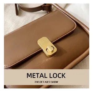 Close-up of golden matte hardware twist lock on brown textured leather crossbody bag