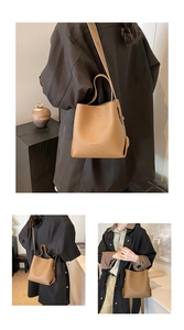 Detail of brown litchi pattern leather bucket bag with top handle and logo embossing