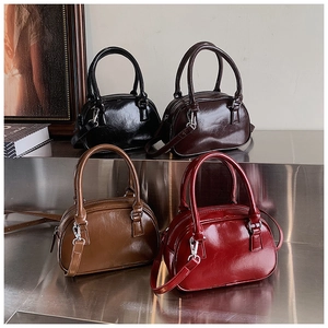Detail view of four retro bowling bags in burgundy, black, and brown with glossy finish