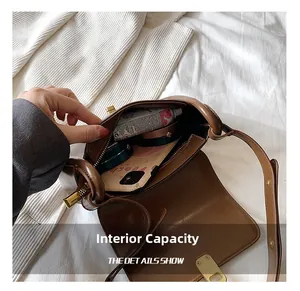 Detail view showing large interior capacity of brown leather shoulder bag with gold clasp