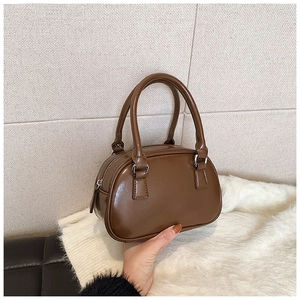 Detail of deep brown glossy leather bowling bag featuring silver metallic hardware