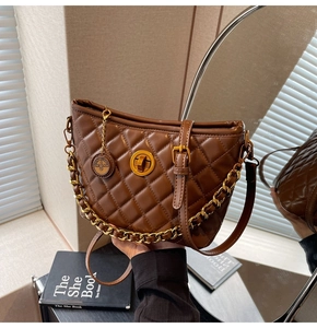 Close-up of brown quilted leather bag with gold circular twist lock and thick chain strap