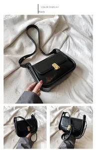 Detail view of black glossy leather crossbody bag with gold metal twist lock and strap