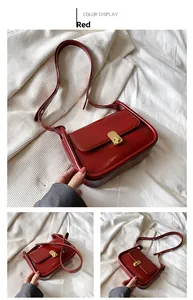 Detail of vintage red leather crossbody bag with golden rotating metal lock buckle