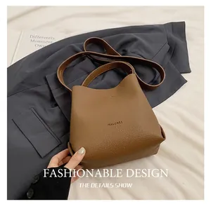 Detailed view of brown litchi pattern leather bucket bag on trench coat background