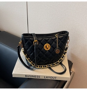 Detail of black quilted leather shoulder bag with gold chain strap and buckle