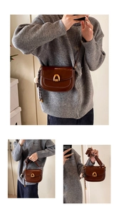 Details einer braunen Satteltasche mit goldener U-Schnalle und flauschigem Pompon-Anhänger