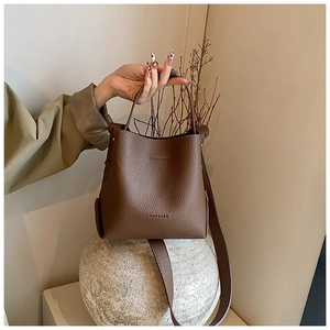 Detail shot of brown lychee grain leather bucket bag with top handle and logo