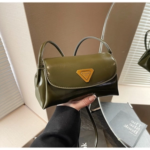Detail of a dark olive green vintage wax leather pillow bag with gold triangular plaque