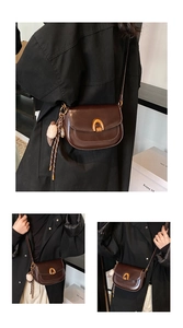 Details der dunkelbraunen Satteltasche mit goldener Hufeisenschnalle und Plüsch-Anhänger