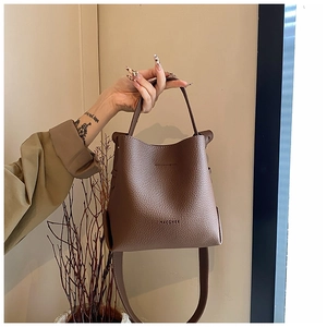 Close-up of brown litchi pattern leather bucket bag with embossed logo and sturdy handle
