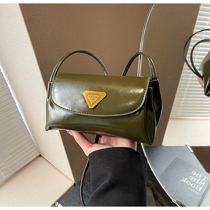 Detail of vintage olive green faux leather crossbody bag with triangular gold logo