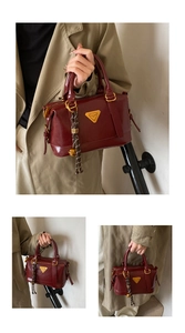 Detail of burgundy Boston bag with golden bell pendant and woven tassel accessory
