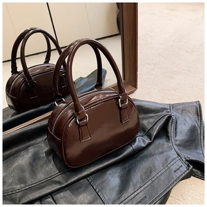 Detail view of brown patent leather Boston bag with glossy finish and silver zippers