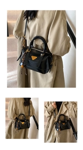 Detail of a black patent leather handbag with a triangle logo and gold hardware accents