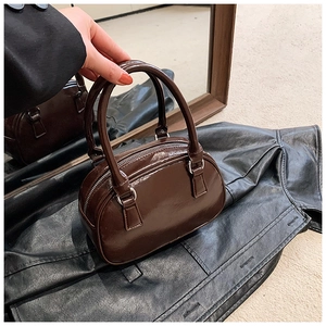 Close-up of a glossy dark brown patent leather bowling bag with vintage handles