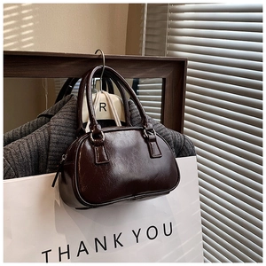 Detail of a dark brown glossy leather bowling bag on a minimal decorative display