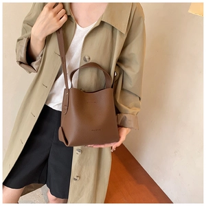 Detail of a dark brown lychee leather bucket bag with top handle and crossbody strap