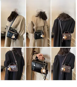 Detail view of vintage-style crossbody bag in black and brown with baseball glove charm