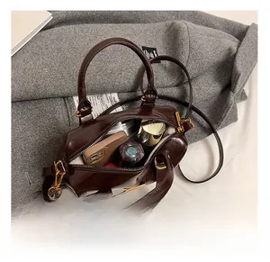 Detail view of the spacious inner capacity of this dark brown glossy Boston handbag