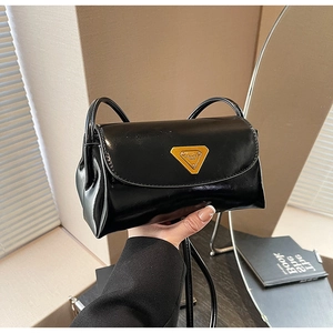 Close-up of black polished wax leather handbag featuring a vintage gold triangle emblem